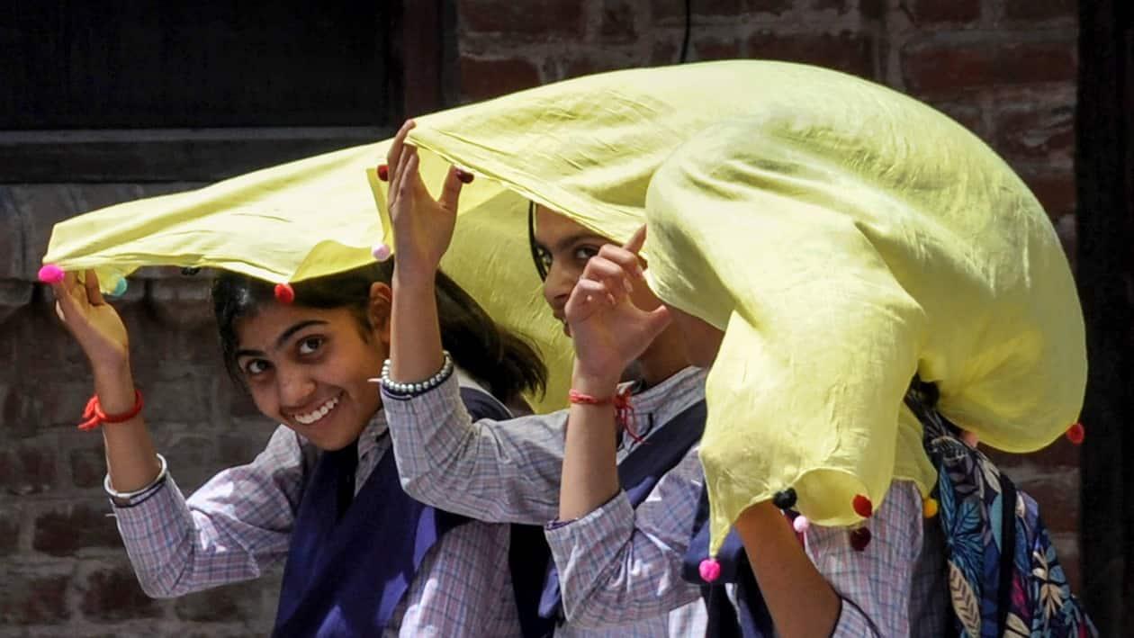 Amritsar: Students use a scarf to shield themselves from the hot summer sun, in Amritsar, Thursday, April 13, 2023. (PTI Photo)(PTI04_13_2023_000170B)