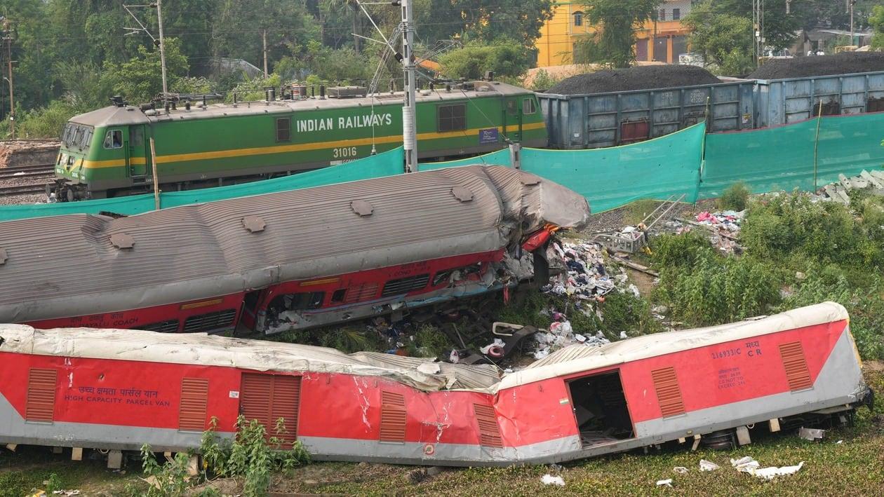 Balasore: A train runs past derailed coaches after train services resumed on the section where the accident happened on Friday, near Bahanga Bazar railway station in Balasore district, Tuesday, June 6, 2023. 
